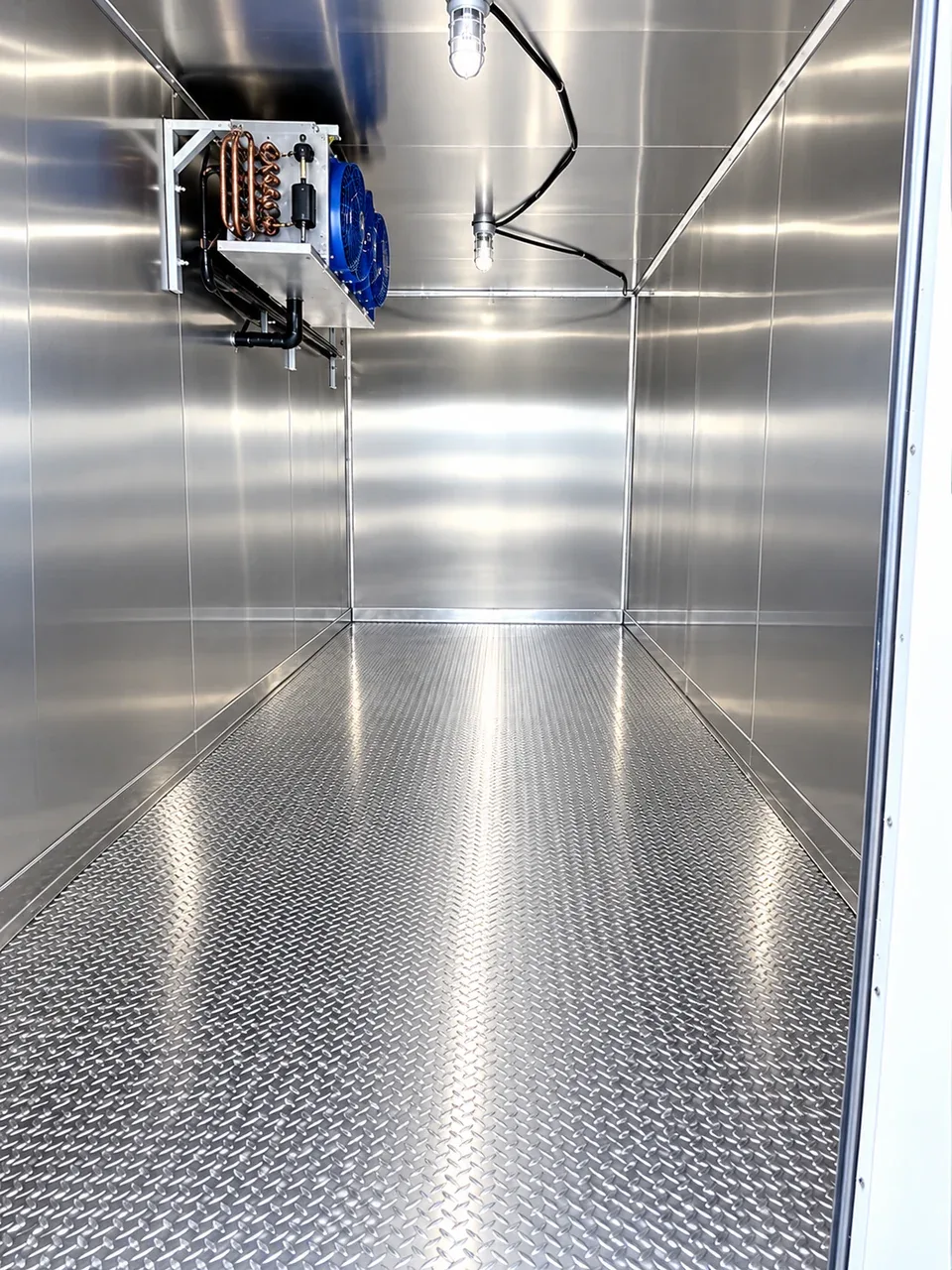 Insulated refrigerated interior with metal walls and a ceiling-mounted cooling unit