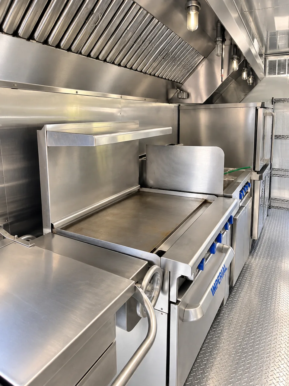 Flat-top cooking equipment beneath a stainless exhaust hood