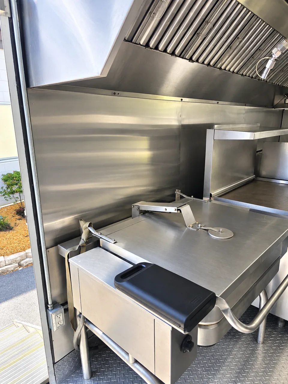 Tilting cooking skillet beneath a stainless exhaust hood
